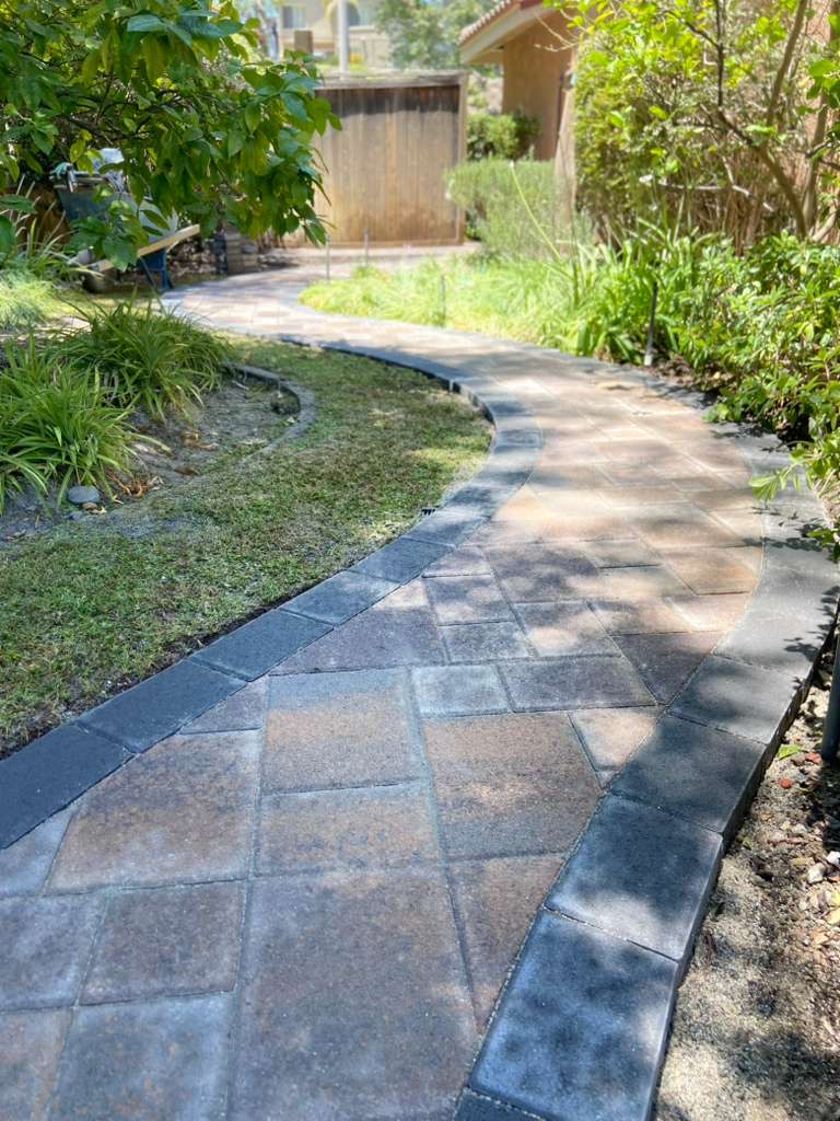 Curved paver pathway through lush garden landscaping