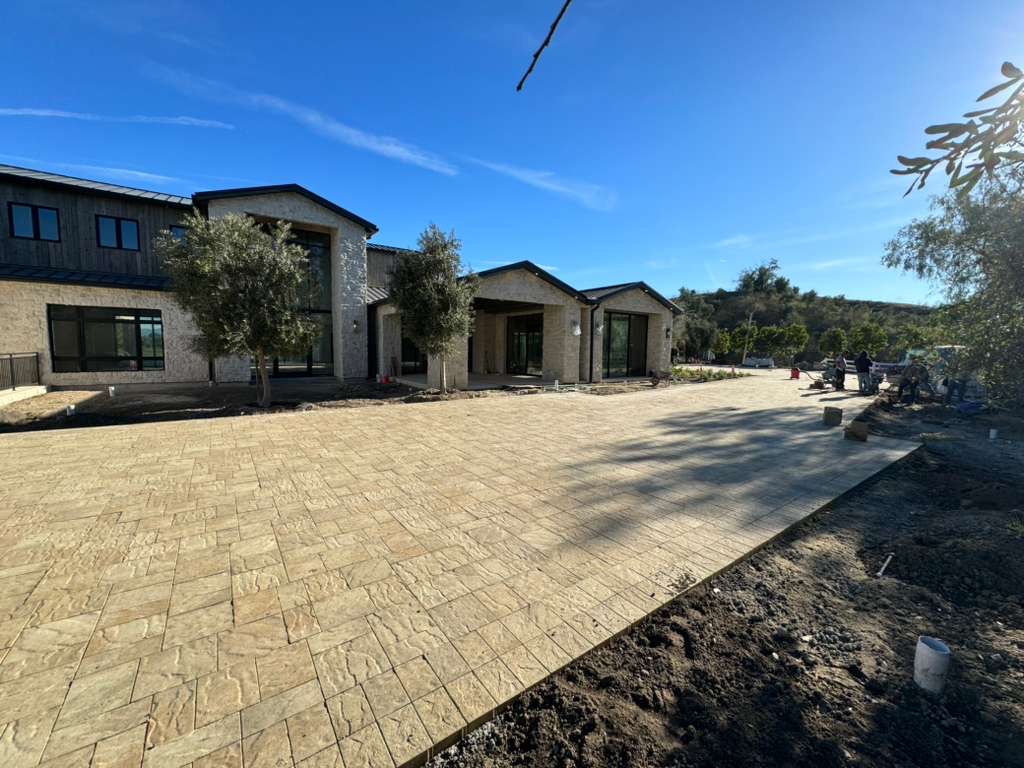 Luxury estate with expansive stamped paver driveway and olive trees