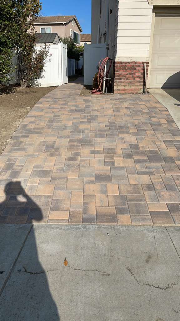 Residential paver walkway alongside house with brick pillar